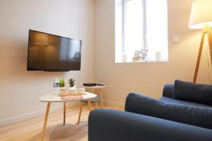 a living room with a couch and a table with a tv at LocationsTourcoing - Le Carnot in Tourcoing