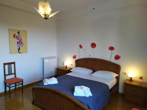 een slaapkamer met een bed en een stoel en bloemen aan de muur bij Bel appartement dans la campagne étrusque in Vignanello