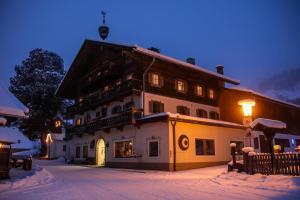 un gran edificio en la nieve por la noche en Kraftquelle Herrnmühle, en Bramberg am Wildkogel
