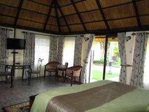 1 dormitorio con 1 cama, mesa y sillas en Art Lodges en Harare