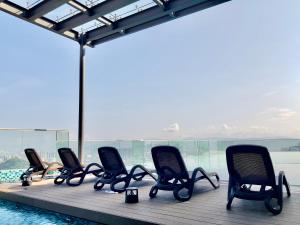una fila de sillas sentadas en un muelle junto a una piscina en EkoCheras Suite by MOKA, en Kuala Lumpur