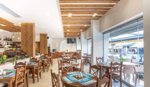 a restaurant with wooden tables and chairs and windows at Paralia Beach Boutique Hotel in Paralia Katerinis
