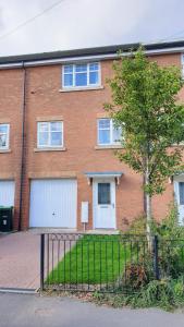 uma casa de tijolos com duas portas de garagem e uma árvore em Seymour Road - Birmingham BnBs em Oldbury