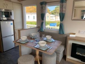 une cuisine et une salle à manger avec une table en bois et de la vaisselle dans l'établissement Shorefield country Park,, à Milford on Sea
