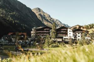 un complejo con una montaña en el fondo en Verwöhnhotel Wildspitze, en Sankt Leonhard im Pitztal