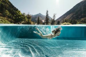 una mujer está en el agua en una piscina en Verwöhnhotel Wildspitze, en Sankt Leonhard im Pitztal