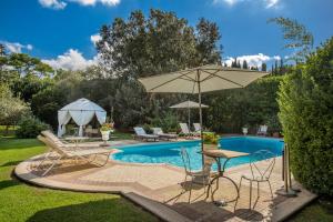 a swimming pool with a table and an umbrella at La Gaura Guest House in Casal Palocco