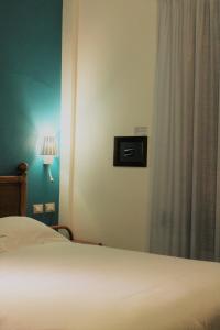 a bedroom with a bed and a lamp and a curtain at Hotel Medusa in Lampedusa