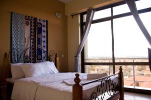 een slaapkamer met een bed en een groot raam bij Lilac Elevate Inn in Karatu