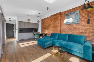 a living room with a blue couch and a brick wall at Aparthotel Krzywa Kamienica in Łódź