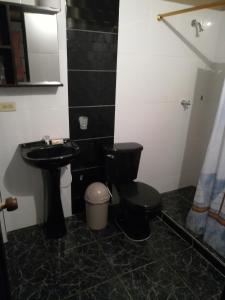 a bathroom with a black toilet and a sink at Un lugar para descansar in Palestina