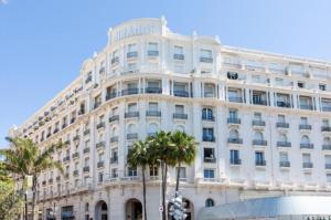 ein großes weißes Gebäude mit Palmen davor in der Unterkunft PALAIS MIRAMAR CROISETTE APART 1 MIN CARLTON in Cannes