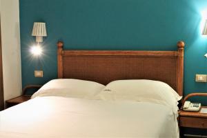 a bedroom with a white bed with a blue wall at Hotel Medusa in Lampedusa