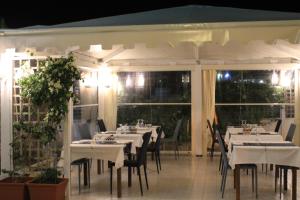 a restaurant with white tables and chairs on a patio at Hotel Medusa in Lampedusa