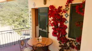 a balcony with a table and two windows with flowers at Appartamento giumin in Corniglia