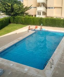 tres personas están sentadas en una piscina en Apartamento Gasparot, en Villajoyosa