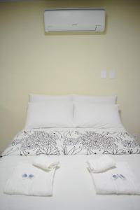 a white bed with white sheets and towels on it at Nova Suíte - centro de Domingos Martins + Café da manhã in Domingos Martins
