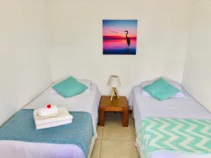 2 Einzelbetten in einem Zimmer mit einem Tisch in der Unterkunft Unique Hotel & Suites in Punta Del Diablo