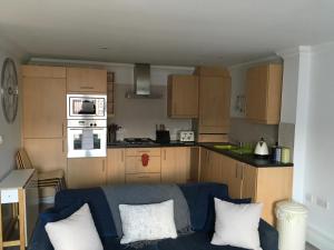 a living room with a blue couch and a kitchen at Godwin Court 21 in Swindon