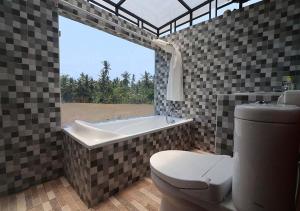Villa Angel D'Uma في Jasri: حمام مع مرحاض وحوض استحمام مع نافذة