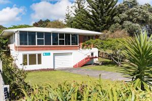 a white house with a garage in a yard at Te Ra Waitangi in Paihia