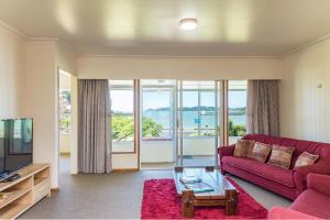 a living room with a red couch and a tv at Te Ra Waitangi in Paihia