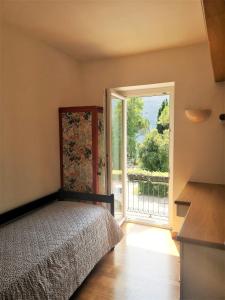 Un dormitorio con una cama y una puerta corrediza de vidrio. en la casetta, en Abbadia Lariana