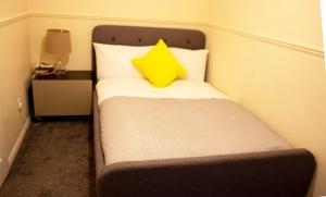 Una cama pequeña con una almohada amarilla. en Kempston Cosy Lodge, en Bedford