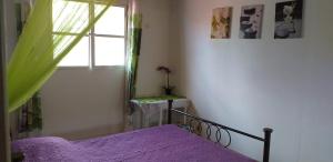 a bedroom with a purple bed and a window at Kaloan in Capesterre-Belle-Eau