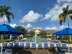 una piscina con sillas y sombrillas azules en Venetian Bay Villages Resort, en Kissimmee