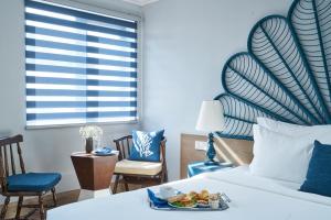 a hotel room with a bed with a tray of food on it at Sofiana My Khe Hotel & Spa- Rooftop Pool Bar in Danang