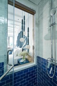 a blue tiled bathroom with a shower and a glass window at Sofiana My Khe Hotel & Spa- Rooftop Pool Bar in Danang