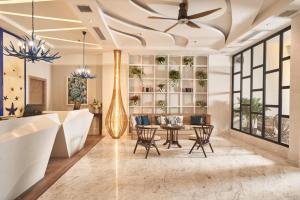 a living room with a ceiling fan and a table at Sofiana My Khe Hotel & Spa- Rooftop Pool Bar in Danang