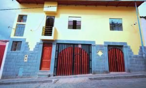 a building with red doors and windows on a street at LA CUSQUEÑITA in Cusco