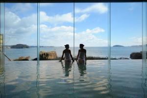 two people sitting in the water in a swimming pool at Minami Sanriku Hotel kanyo in Shizukawa