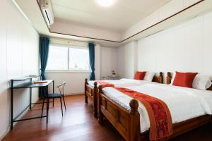 a bedroom with two beds and a desk and a window at Sukhumvit 101 HOTEL in Bangkok