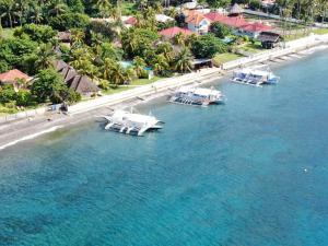 Tre barche sono ormeggiate nell'acqua accanto a una spiaggia di Thalatta Resort a Zamboanguita