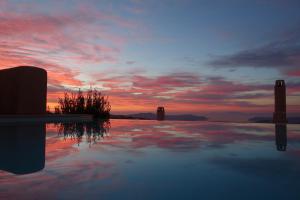 a sunset with a reflection in a pool of water at Voreina Gallery Suites in Pyrgos
