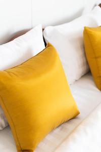 a yellow pillow on a bed with white pillows at Sukhumvit 101 HOTEL in Bangkok