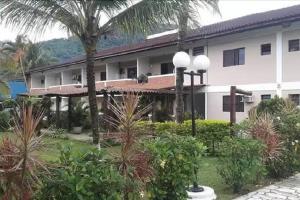 a large white building with palm trees in front of it at Apartamento Condomínio Boiçucanga Flat N 39 - Apto 10 in Boicucanga