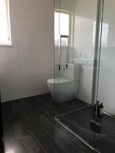 a bathroom with a toilet and a glass shower at TAURANGA, Bay of Plenty in Tauranga