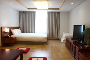 a hotel room with a television and a bed at Maison Glad Jeju in Jeju