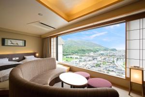 Habitación con ventana grande, cama y sofá. en Yumoto Konpira Onsen Hananoyu Kobaitei, en Kotohira