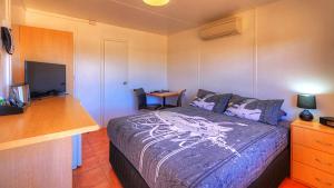 a bedroom with a bed and a desk with a television at Halls Creek Motel in Halls Creek