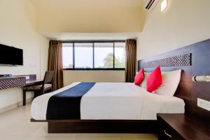 een slaapkamer met een groot wit bed met rode kussens bij Hotel Xec Residency in Madgaon