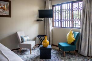 a hotel room with a bed and two chairs and a window at Pro Active Guest House in Pretoria