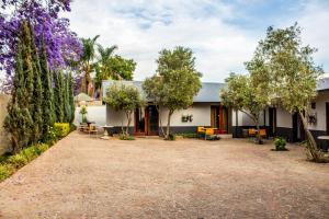 a house with a gravel driveway and trees at Pro Active Guest House in Pretoria