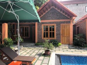ein Haus mit einem Pool und einem grünen Sonnenschirm in der Unterkunft Tam Coc Summer Bungalow in Ninh Bình