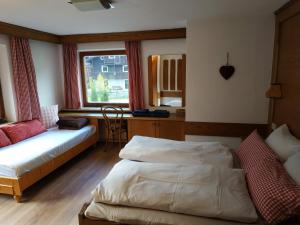een slaapkamer met 2 bedden, een bureau en een raam bij Haus Gartner 4-5 pers appartement in Sulzau