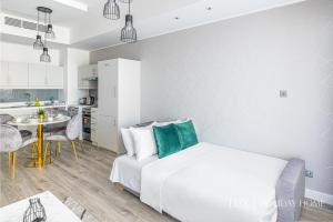 a white bedroom with a bed and a kitchen at LUX - IBN Battuta Residence in Dubai